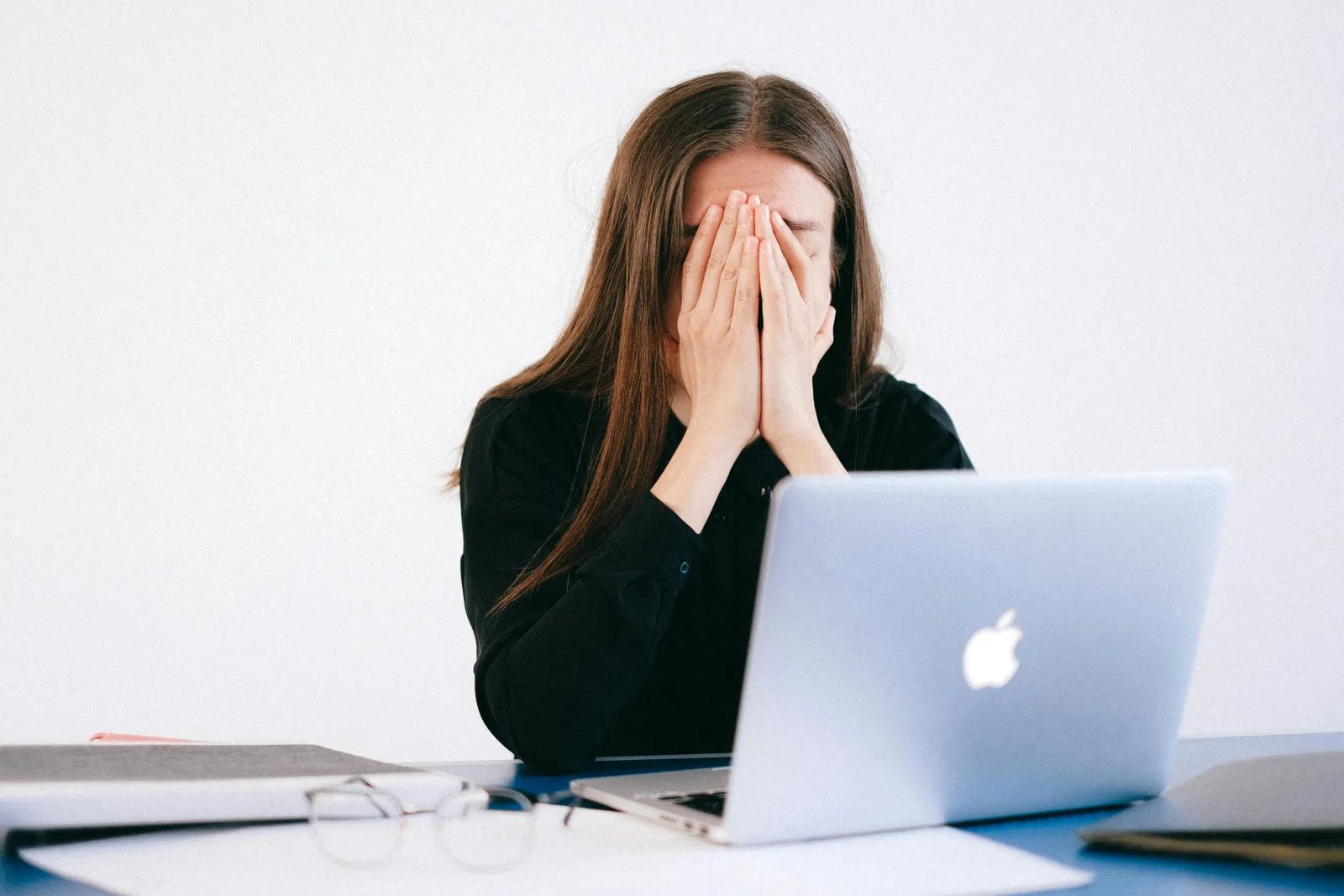 a woman with her hands on her face looking at a laptop