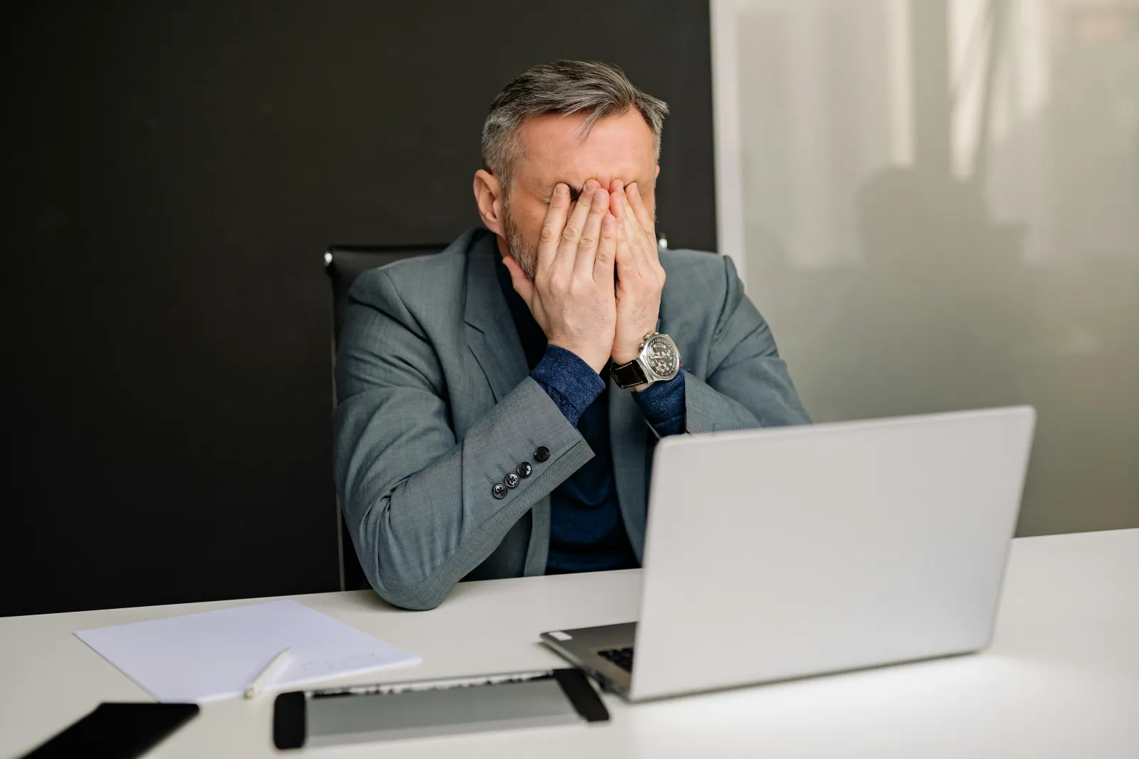a man sitting at a desk with his hand on his face
