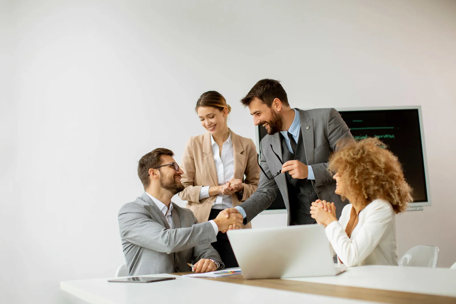 a group of people sitting at a table looking at a laptop