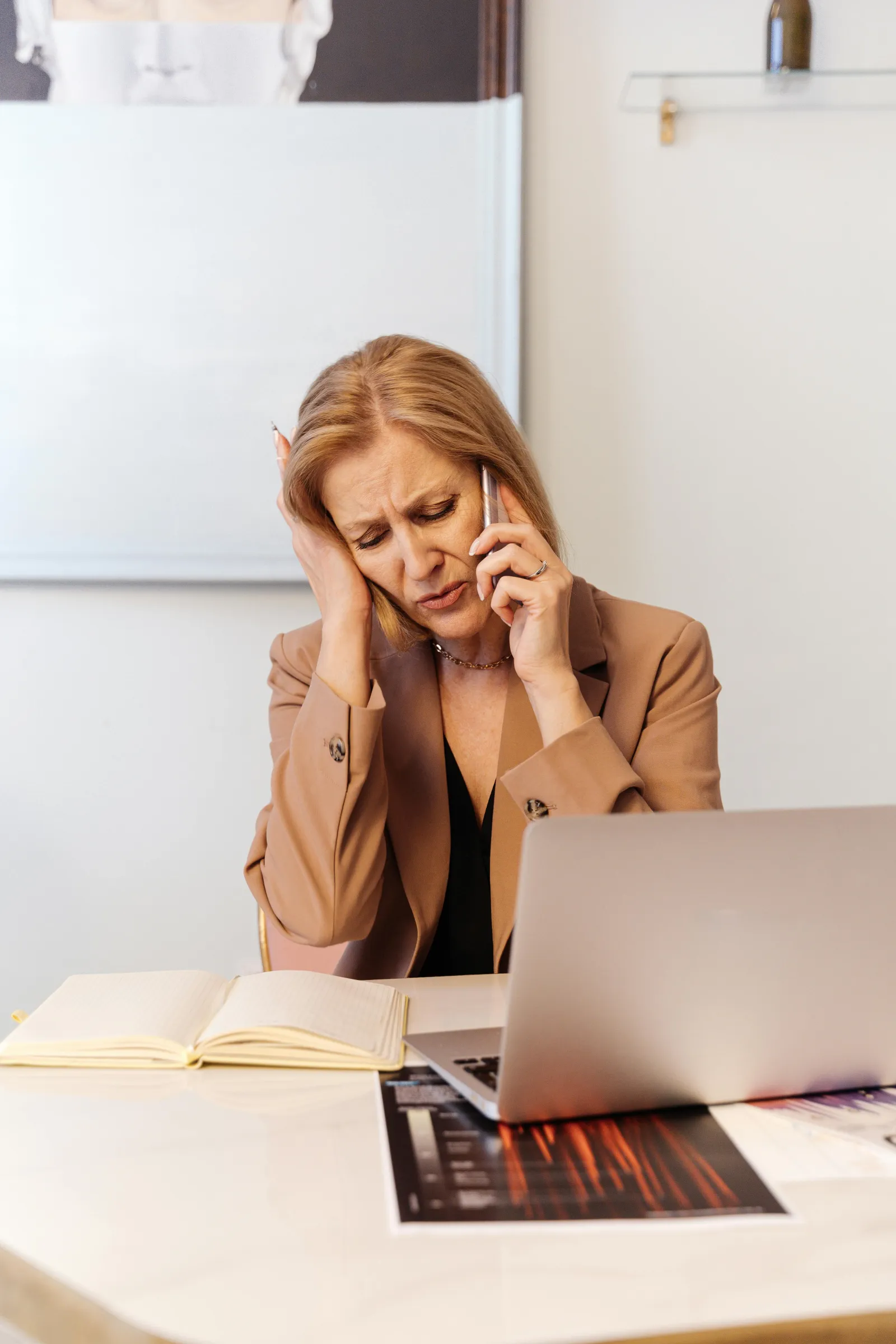 a woman sitting at a desk with her hand on her face